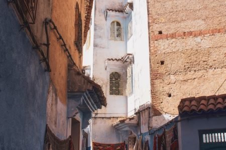people walking between brown and white concrete houses