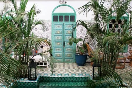 a pool with a green door surrounded by palm trees