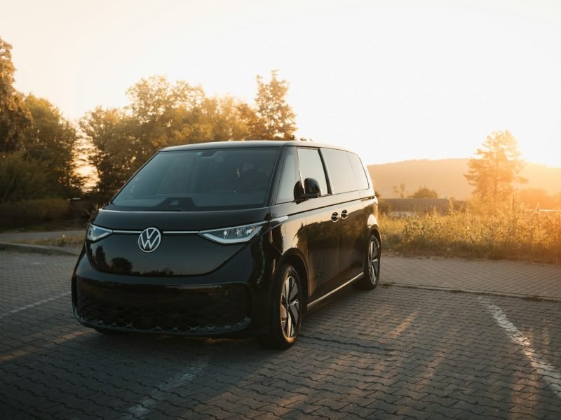 Una furgoneta negra circulando por una carretera junto a un bosque