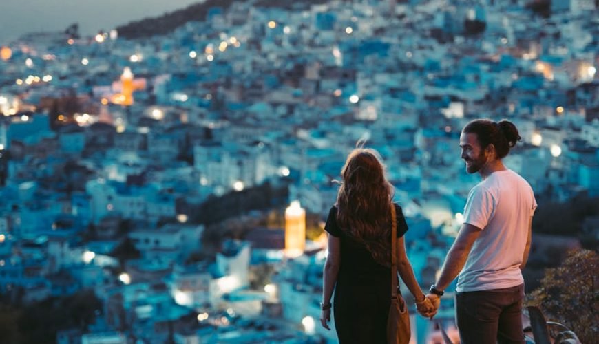 Un couple romantique se tenant la main avec une vue sur Chefchaouen, Morocco au crépuscule.