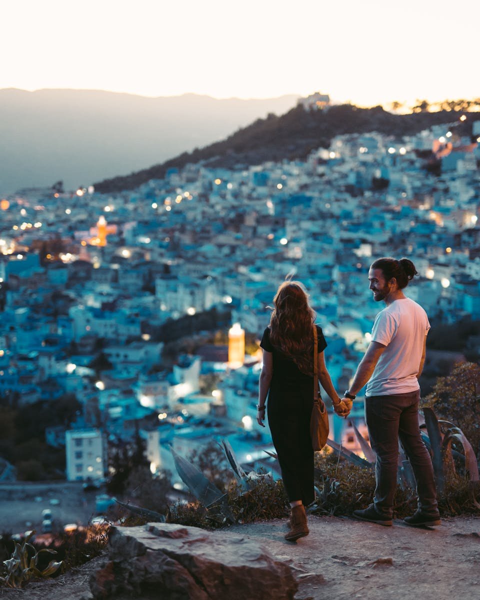 Un couple romantique se tenant la main avec une vue sur Chefchaouen, Morocco au crépuscule.