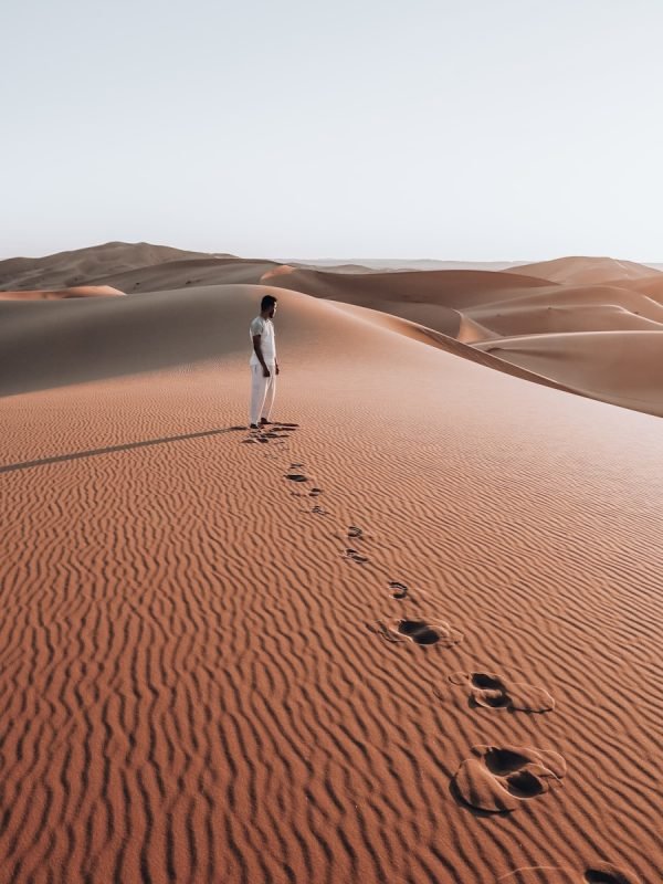 Photo by zakariae daoui person in white shirt walking on desert during daytime